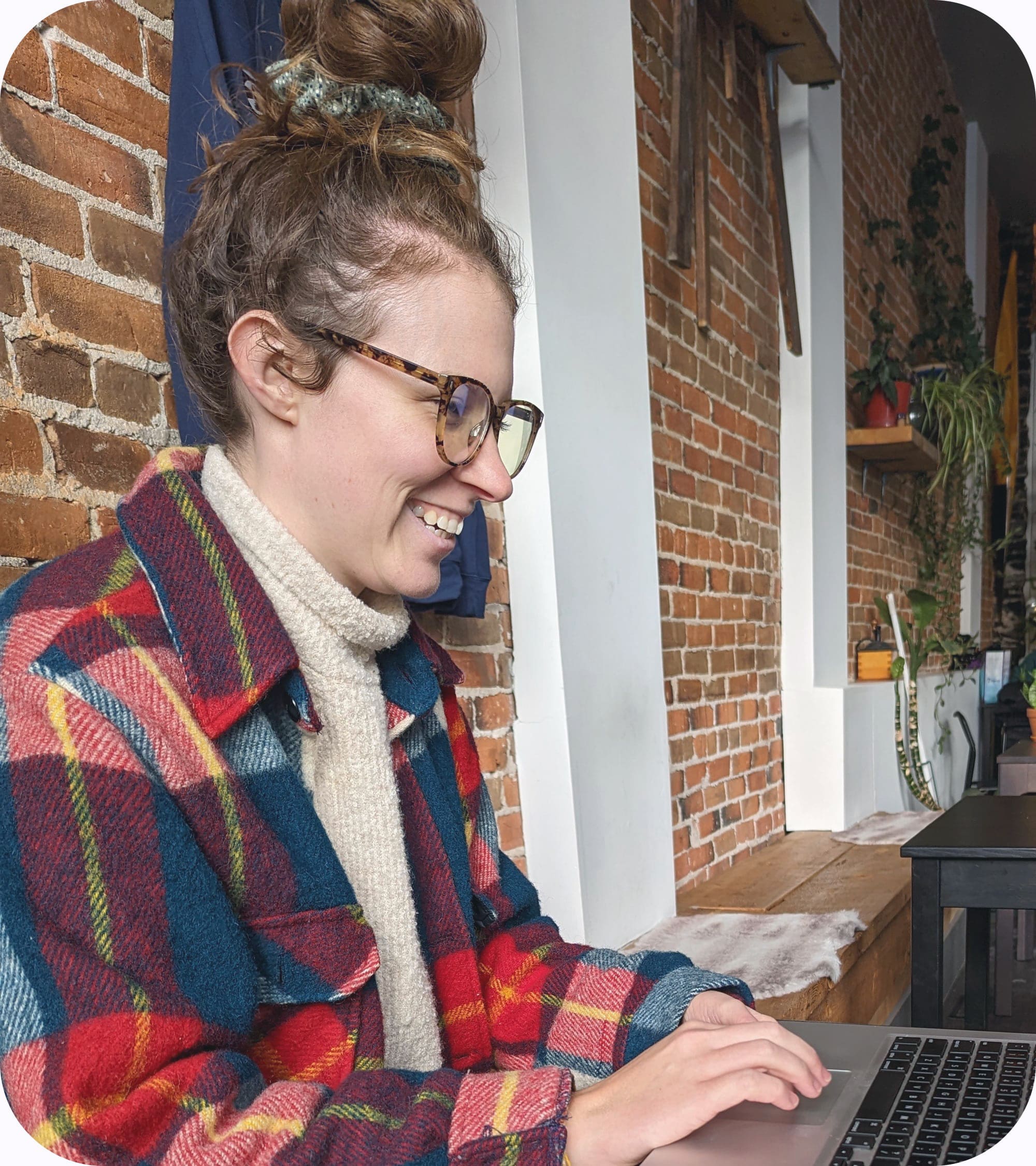 Picture of Julia at a table working on her laptop, smiling.